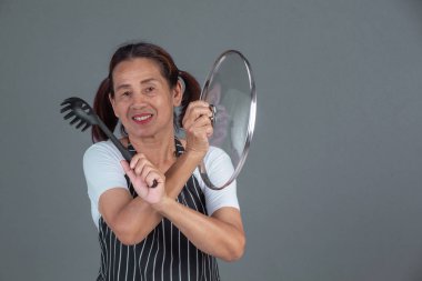 Elinde mutfak gereçleri olan yaşlı bir aşçı..