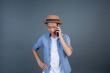 Gri arka planda cep telefonu olan yakışıklı bir genç..