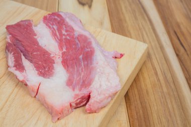 Domuz eti, kahverengi ahşap arka planı olan bir tahta kesme tahtasına konur..