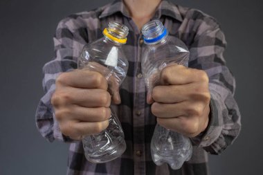 Elindeki su şişesini sıkan erkeğin arka planı gri..