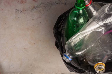 Çöp poşetlerindeki plastik şişelerin arka planı gri..