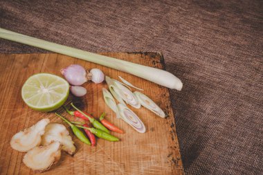 Tom Yum baharatları kahverengi ahşap kesme tahtasına yerleştirilir ve koyu kahverengi ahşap arka planı vardır..