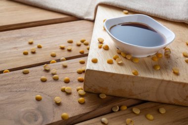 Tahtaya konulan soya sosu ve etrafa saçılmış çiğ soya çekirdekleri..