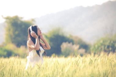 Güzel bir kadın arpa tarlalarında müzik dinliyor..