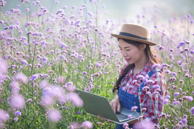 Farmers women are playing notebooks in the flower garden. New generation farmer concept
