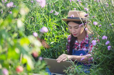 Farmers women are playing notebooks in the flower garden. New generation farmer concept