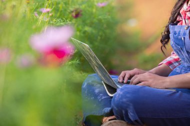 Farmers women are playing notebooks in the flower garden. New generation farmer concept