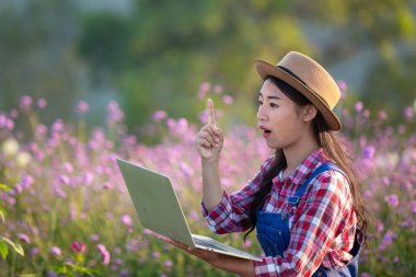 Farmers women are playing notebooks in the flower garden. New generation farmer concept