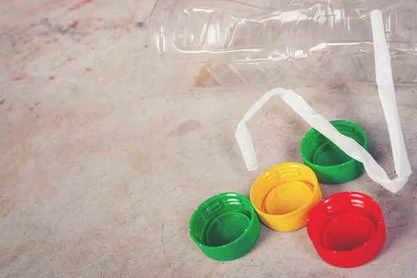 Plastic waste that is placed on a bluish-colored cement floor that is colored.