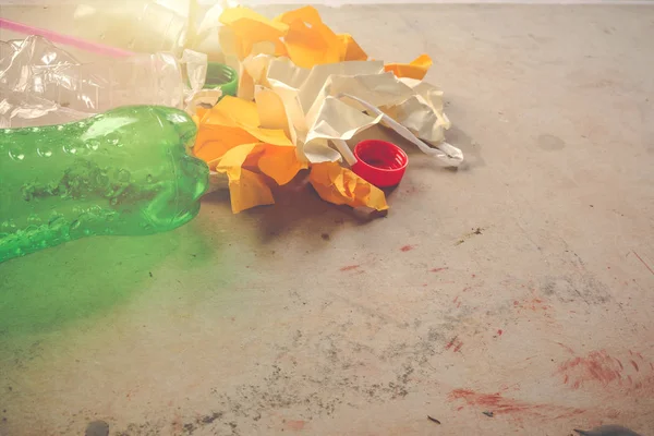 Plastic waste and paper piles placed on a bluish-colored cement floor that color.