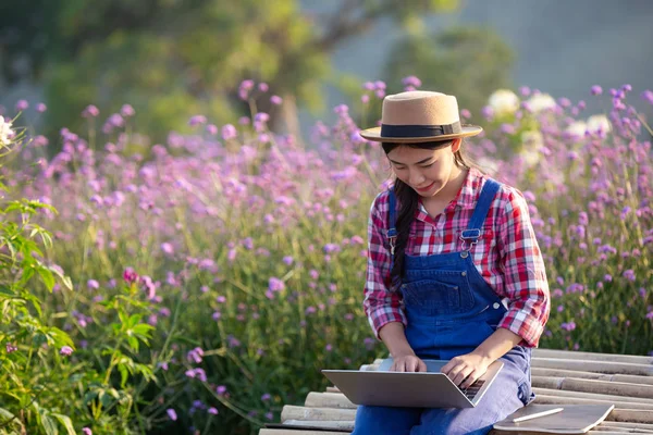 Farmers women are playing notebooks in the flower garden. New generation farmer concept