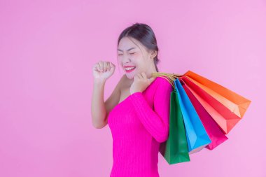 Kızın elinde pembe bir arka planda moda alışveriş çantası ve güzellik var..