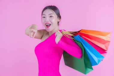 Kızın elinde pembe bir arka planda moda alışveriş çantası ve güzellik var..