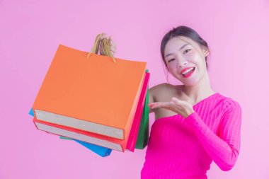 Kızın elinde pembe bir arka planda moda alışveriş çantası ve güzellik var..