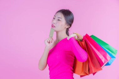 Kızın elinde pembe bir arka planda moda alışveriş çantası ve güzellik var..