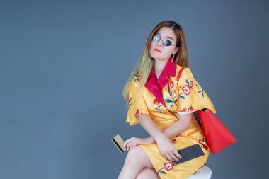 Gri arka planda akıllı kartlar ve cep telefonları tutan kadınlar.