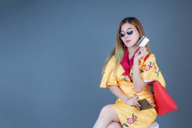 Gri arka planda akıllı kartlar ve cep telefonları tutan kadınlar.