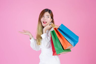 Beautiful white girl holding a shopping bag, fashion and beauty on a pink background.
