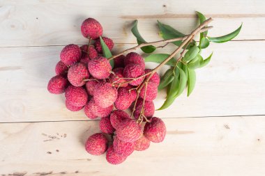 Kırmızı liçi meyvesi ahşap zeminde bir sepete konur..