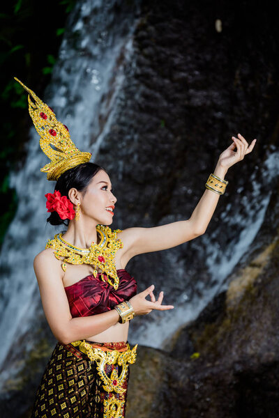 A woman dressed with an ancient Thai dress at the waterfall.