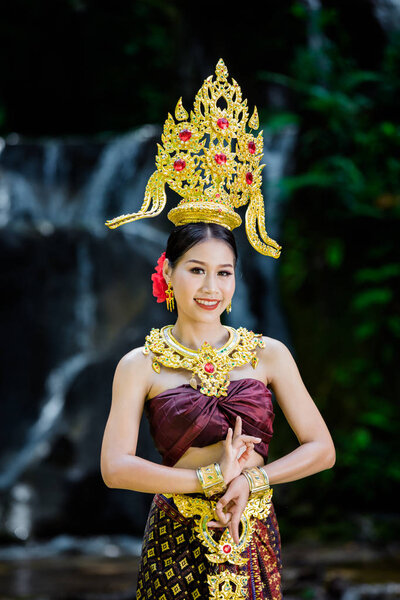 A woman dressed with an ancient Thai dress at the waterfall.