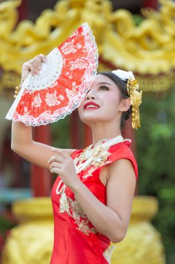 Çinli geleneksel Cheongsam elbiseli Asyalı kadın elinde Çin gazetesi fanı tutuyor..