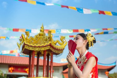 Elinde kağıt yelpaze tutan ve gülümseyen Asyalı güzel bir kız onu mutlu gösteriyor..