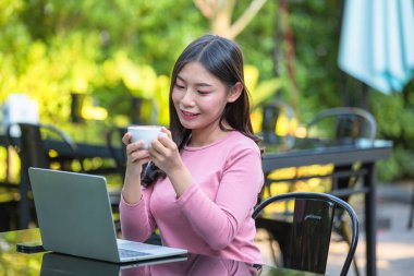 Women are selling products through social media using online notebooks at coffee shops.
