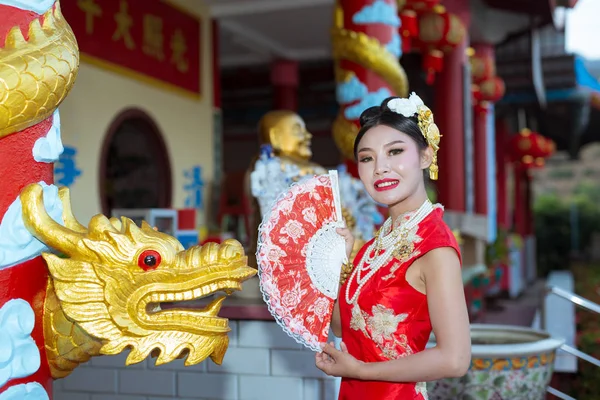 Asian woman with chinese traditional dress cheongsam holding chinese paper fan.