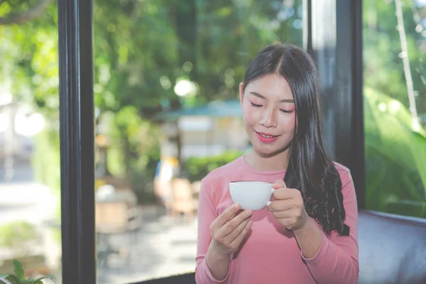 The girl is sipping coffee with pleasure at the coffee shop.