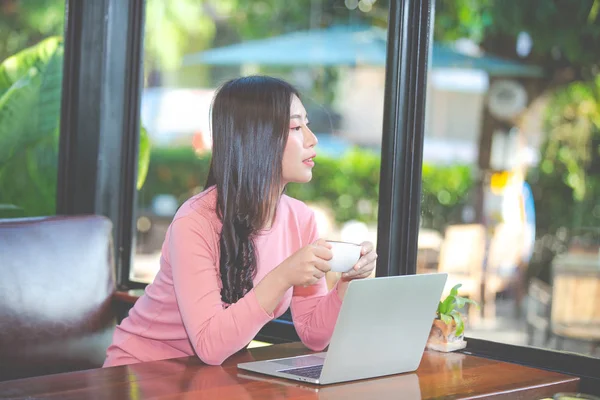 Women are selling products through social media using online notebooks at coffee shops.