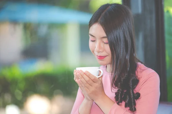 The girl is sipping coffee with pleasure at the coffee shop.