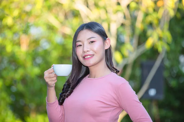 The girl is sipping coffee with pleasure at the coffee shop.