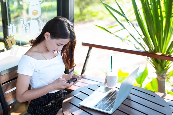 Women are selling products through social media using online notebooks at coffee shops.