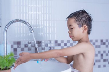 Çocuk dişlerini fırçalıyor ve yüzünü yıkıyor..