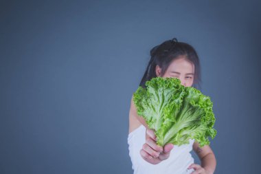 Kız sebzeleri gri arka planda tutuyor..