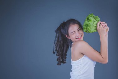 Kız sebzeleri gri arka planda tutuyor..