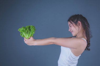 Kız sebzeleri gri arka planda tutuyor..