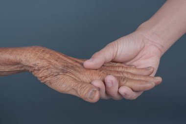 Yaşlı bir kadının elini tutan genç bir kadın..
