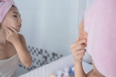 Asyalı kız sivilce sıkıyor.