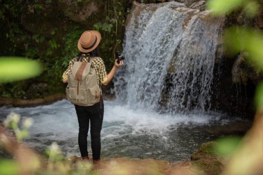 Kadın yürüyüşçüler güzel şelaleler ile kendilerini fotoğraf çekmek. Yürüyüşten sonra rahatlayın