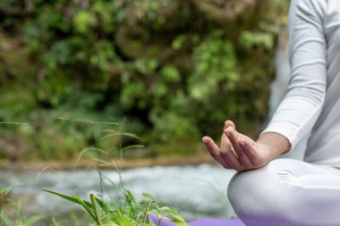 Güzel kızlar parkta yoga oynuyorlar. Ormandaki doğal şelaleler arasında egzersiz konseptleri