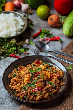 Tayland yemeği malzemeleriyle süslenmiş fesleğen yapraklı kızarmış domuz eti. 