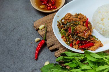 Tayland yemeği malzemeleriyle süslenmiş fesleğen yapraklı kızarmış domuz eti. 