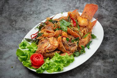 Bitkilerle, limonotlarla, kaffir limon yapraklarıyla ve masa sosuyla pişirilmiş çıtır tilapia balığı..