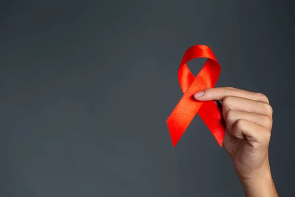 Kadın elinde kırmızı kurdele HIV farkındalığı konsepti Dünya AIDS Günü ve Dünya Cinsel Sağlık Günü.