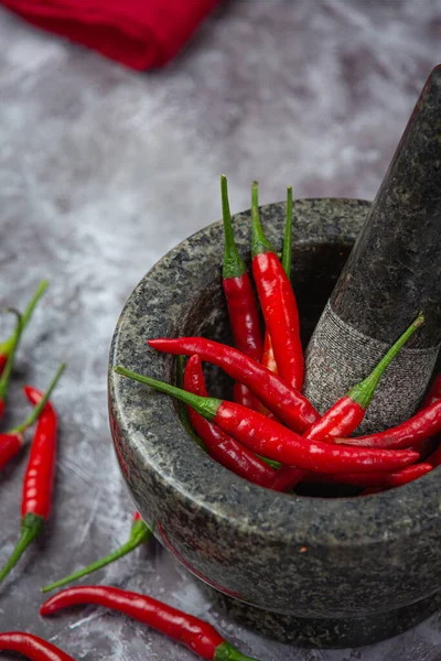 Red chillies are in a stone mortar on a black surface