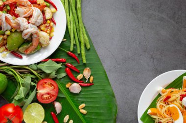 Mısır ve karides ile Som Tum, pirinç eriştesi ve Tayland yemeği malzemeleriyle süslenmiş yeşil salata ile servis edilir..