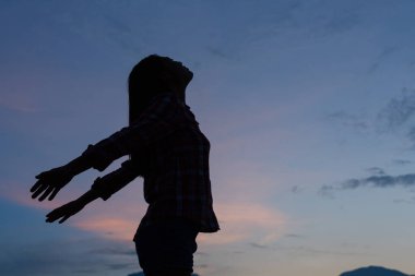 Ayakta duran ve başını dik tutan bir kadının gölgesi.