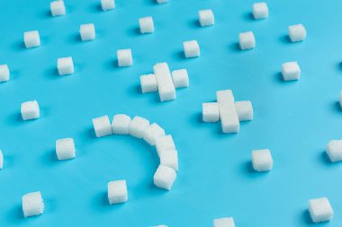 World diabetes day; sugar cubes are arranged in the shape of sad face on blue background